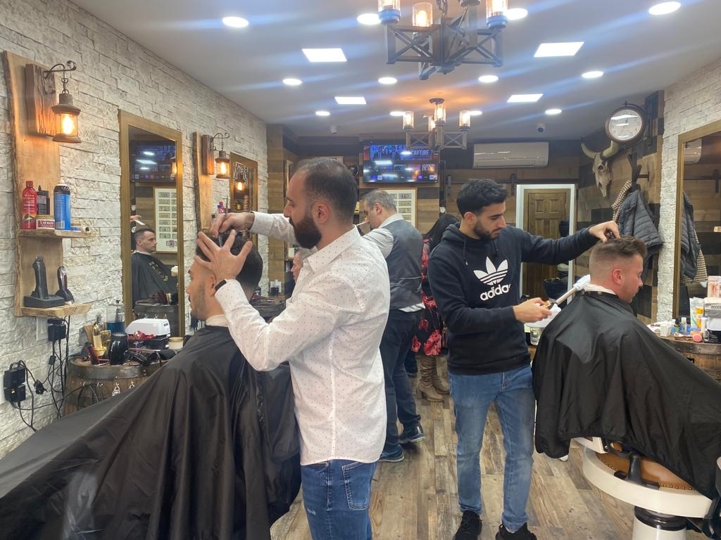 What are the qualifications and experience of the barbers working at Tribeca Barber Shop?